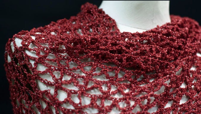 Side view of the red shawl, the shimmering thread catching the light.