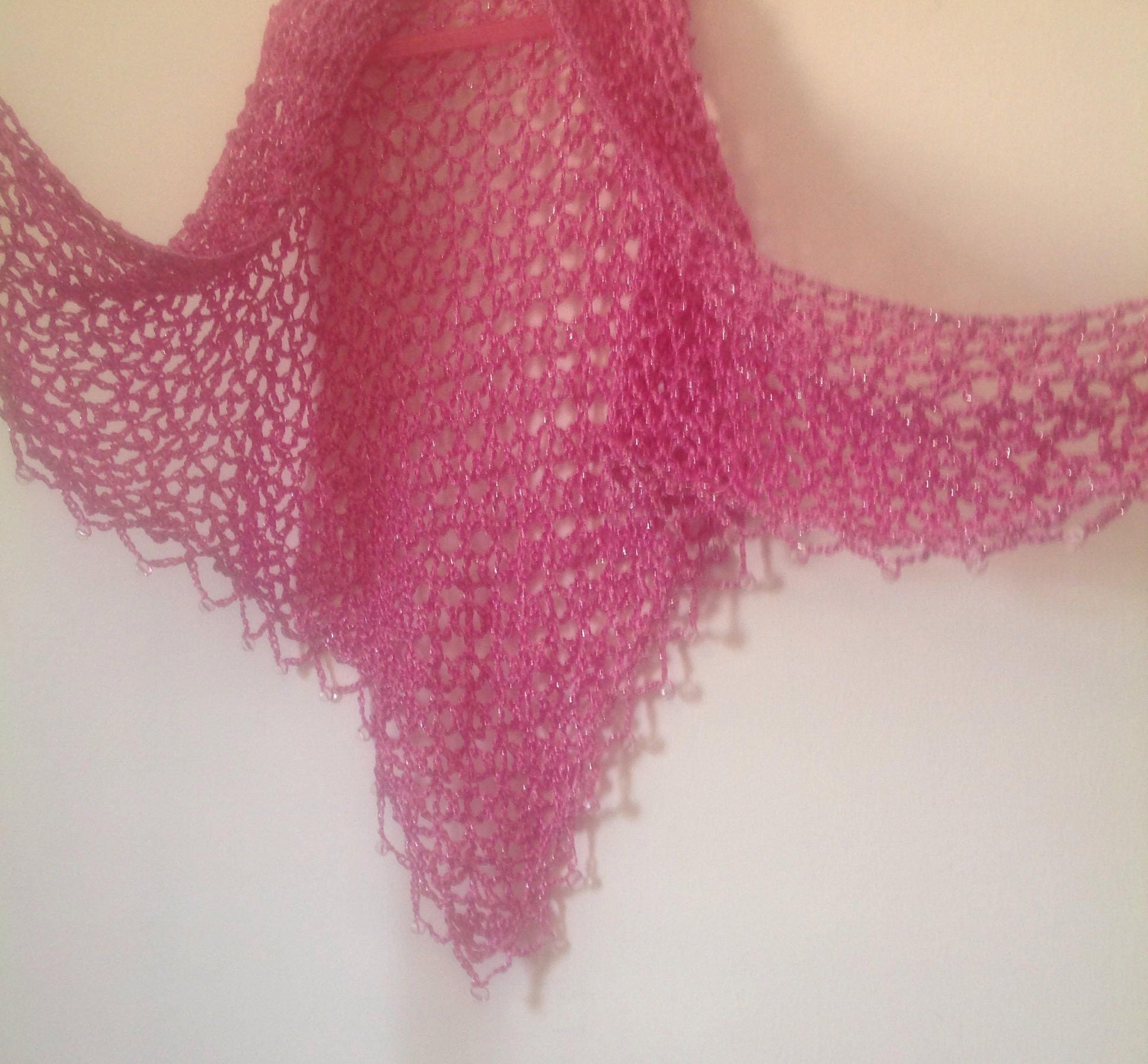 Blush pink shawl spread wide, triangular shape with bead-trimmed edges.