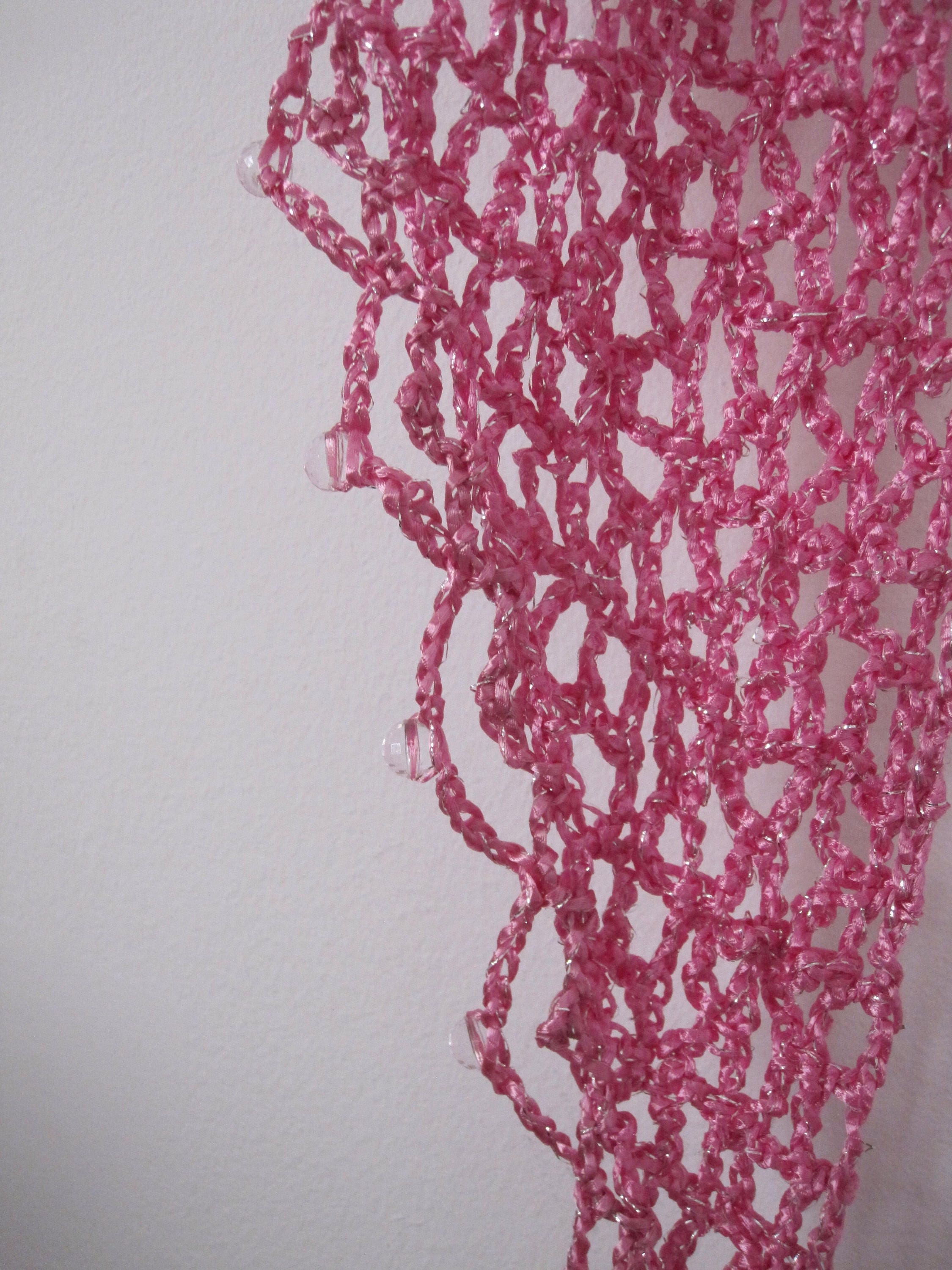 Macro detail of the blush pink crochet stitches and clear faceted beads.