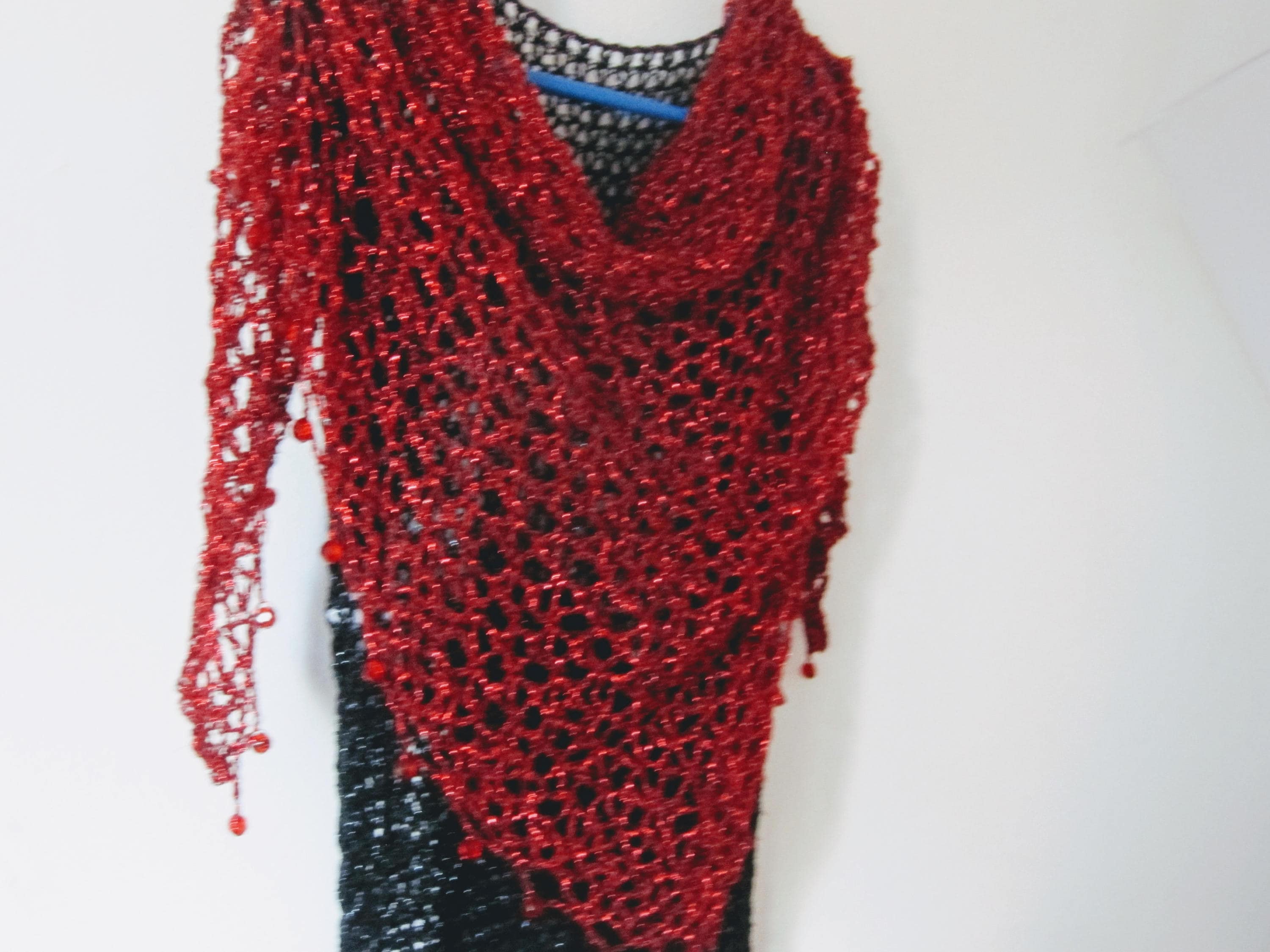Close-up of the red crochet openwork and beaded edge of the shawl.