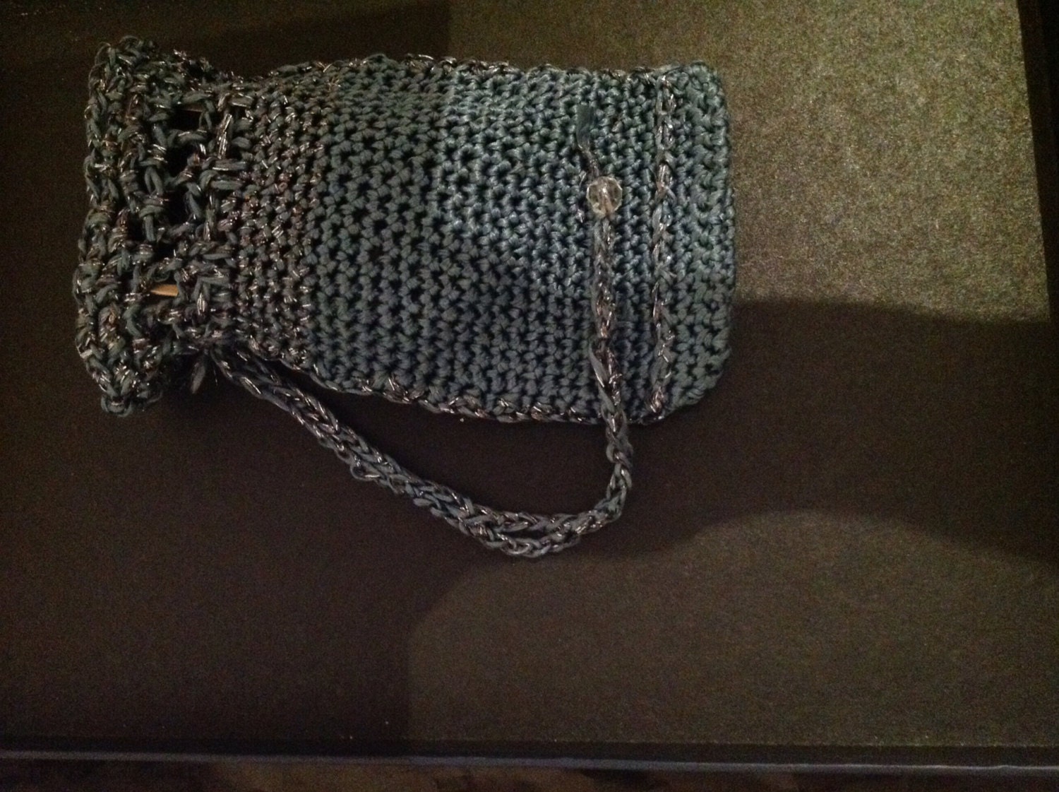 Side view of the gray phone pouch, the shimmering thread catching the light.